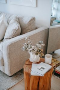 Jasna sofa i drewniany stolik kawowy - pieniek. 